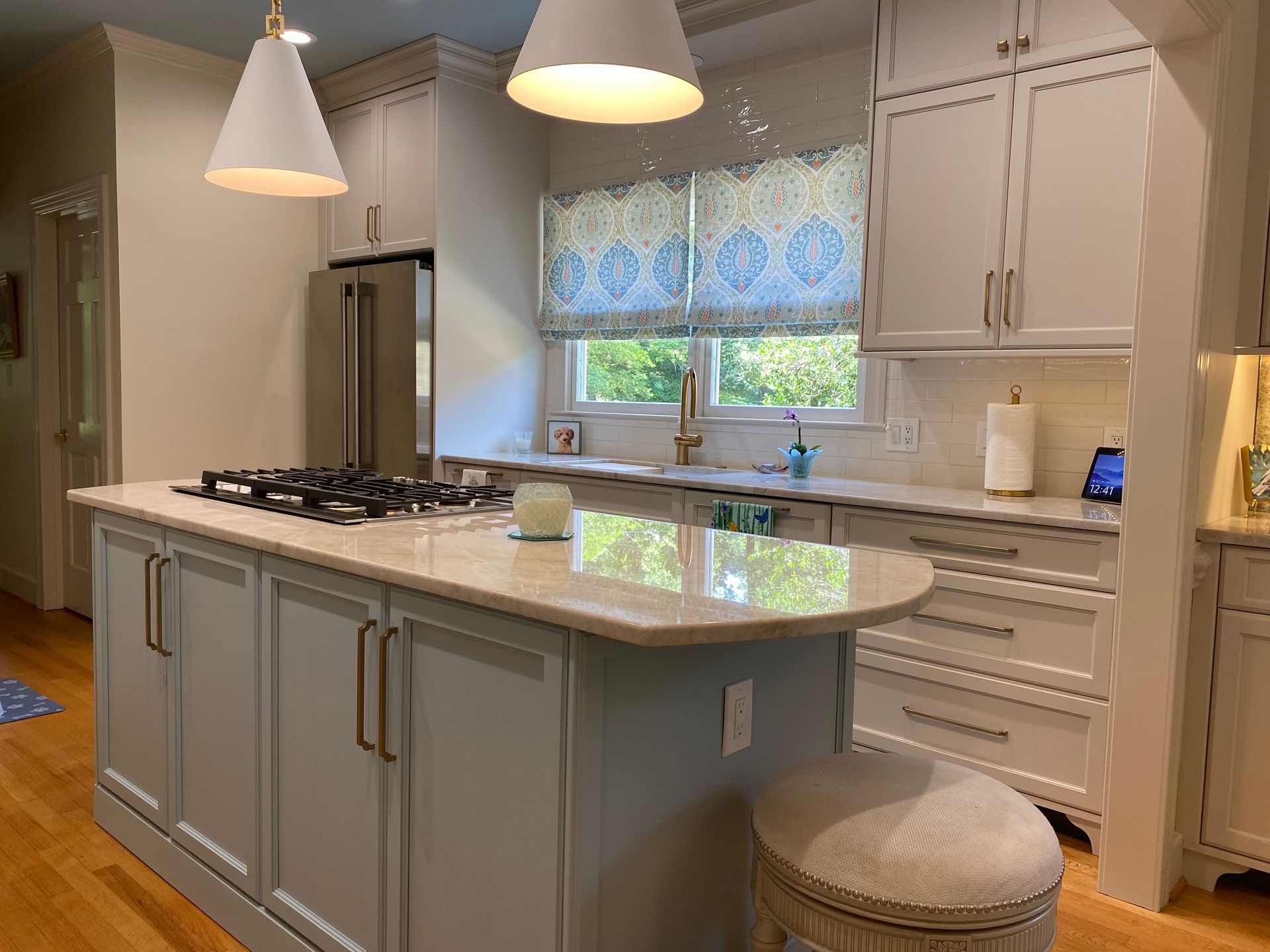 White shaker kitchen with coastal blue island and large gold pull hardware.