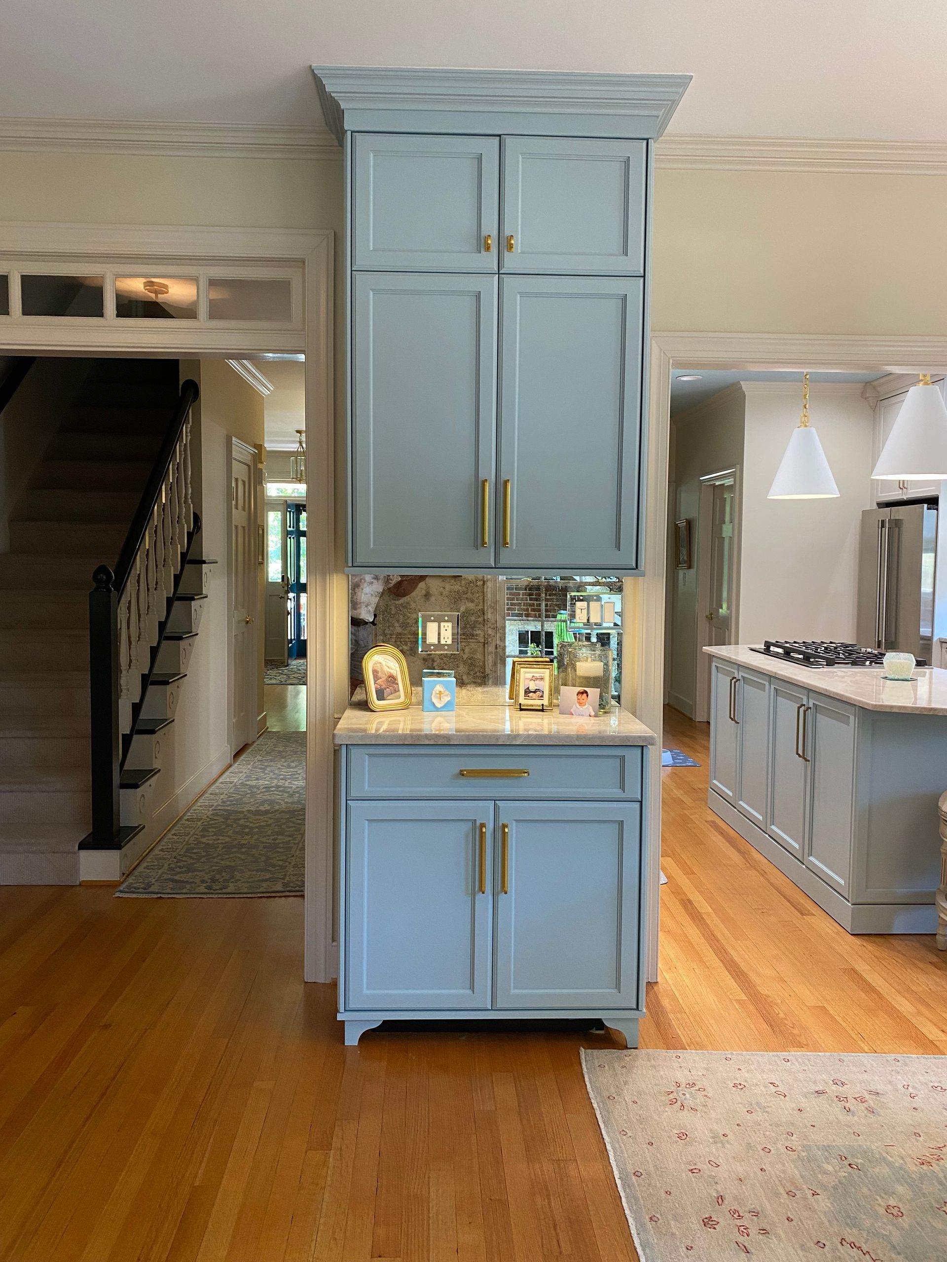 Beverage station made of coastal blue cabinets with gold pull hardware.