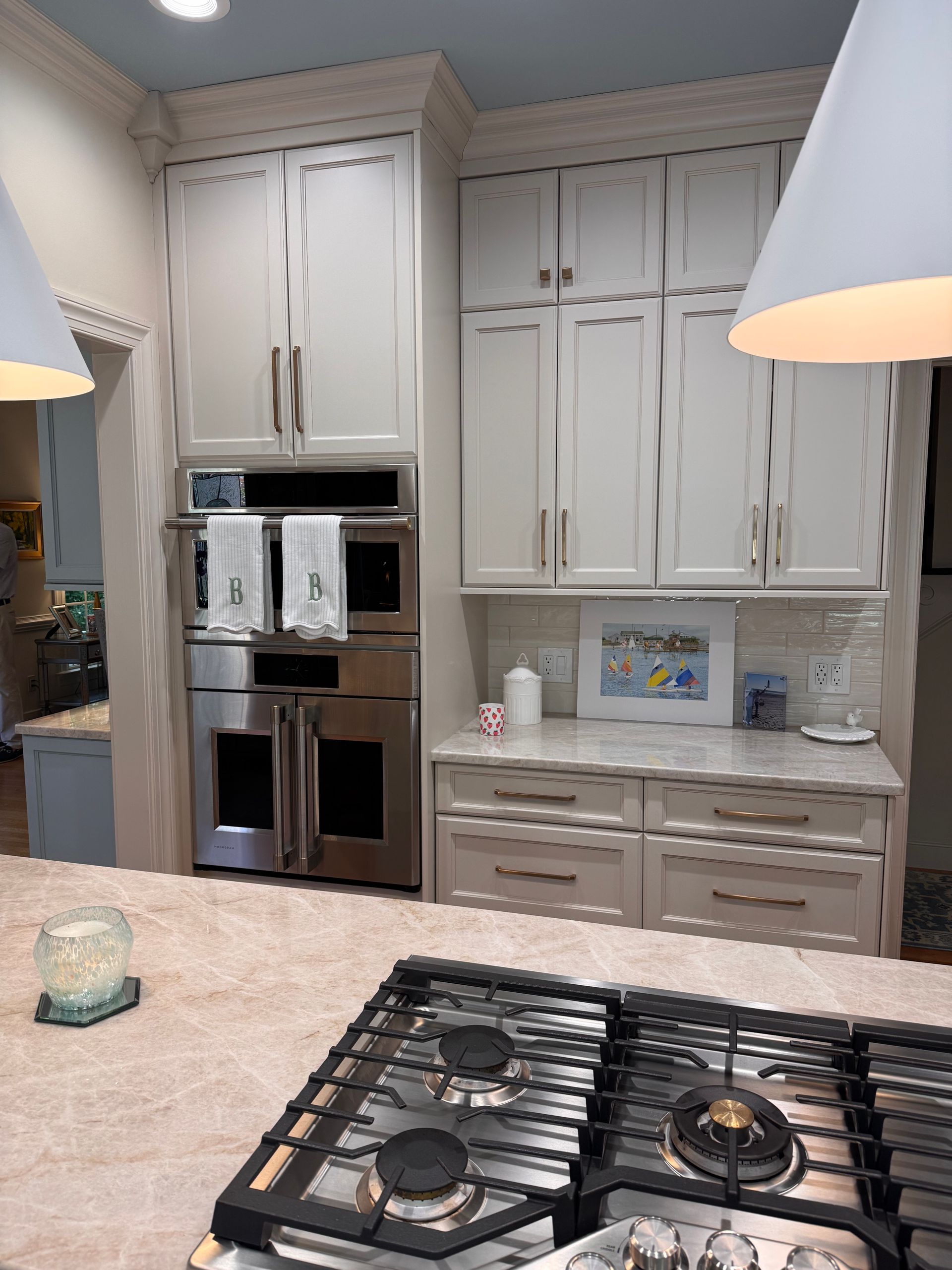 Kitchen with wall microwave and oven combo and white shaker cabinets with gold pull hardware.