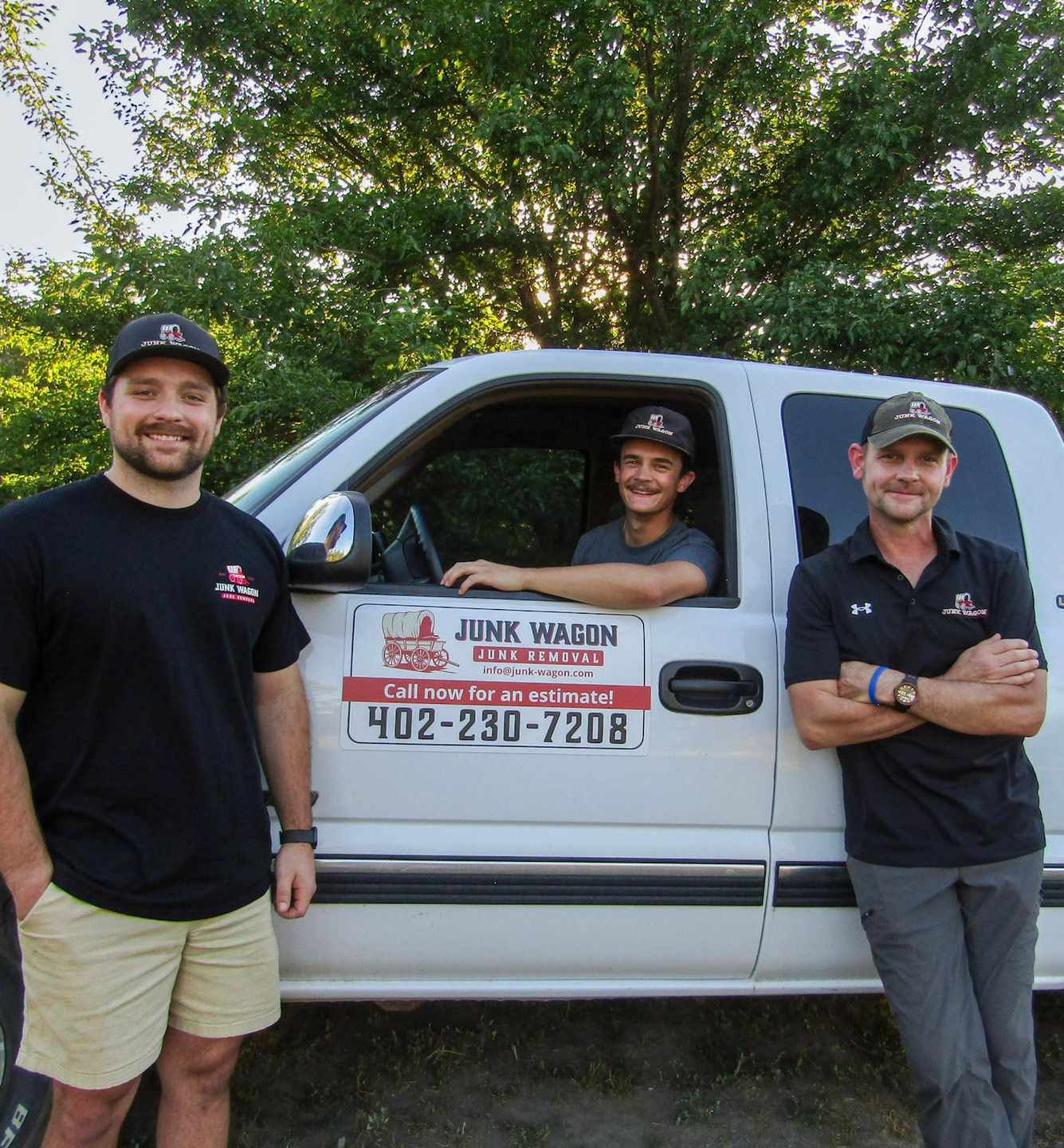 Three smiling workers beside a white service van with a company sign.