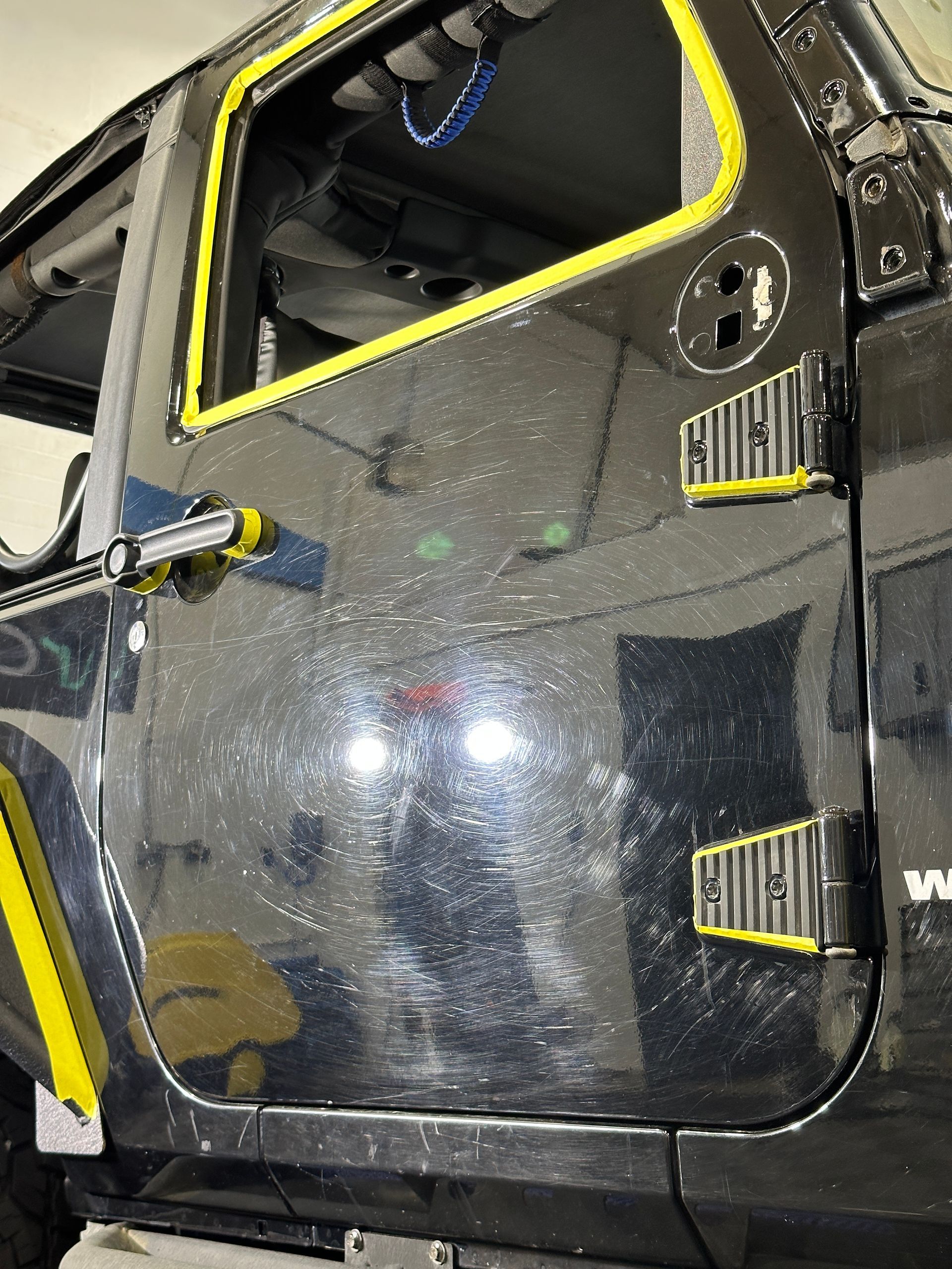 A black jeep with yellow trim is sitting in a garage.