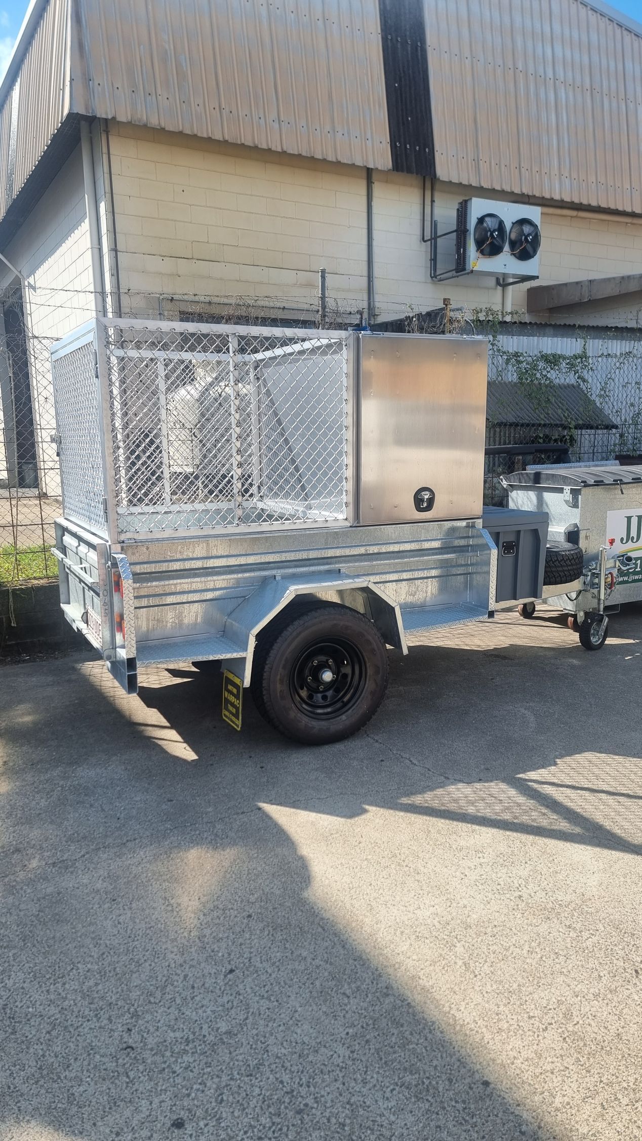 Metal utility trailer with caged sides, parked on pavement, near a building — Mingweld Fabrication in Bungalow, QLD