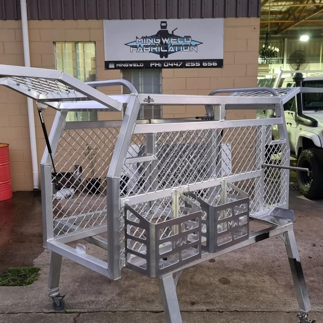 Aluminum fabricated cage with mesh sides, open top, storage baskets, and casters; in front of a shop — Mingweld Fabrication in Bungalow, QLD 