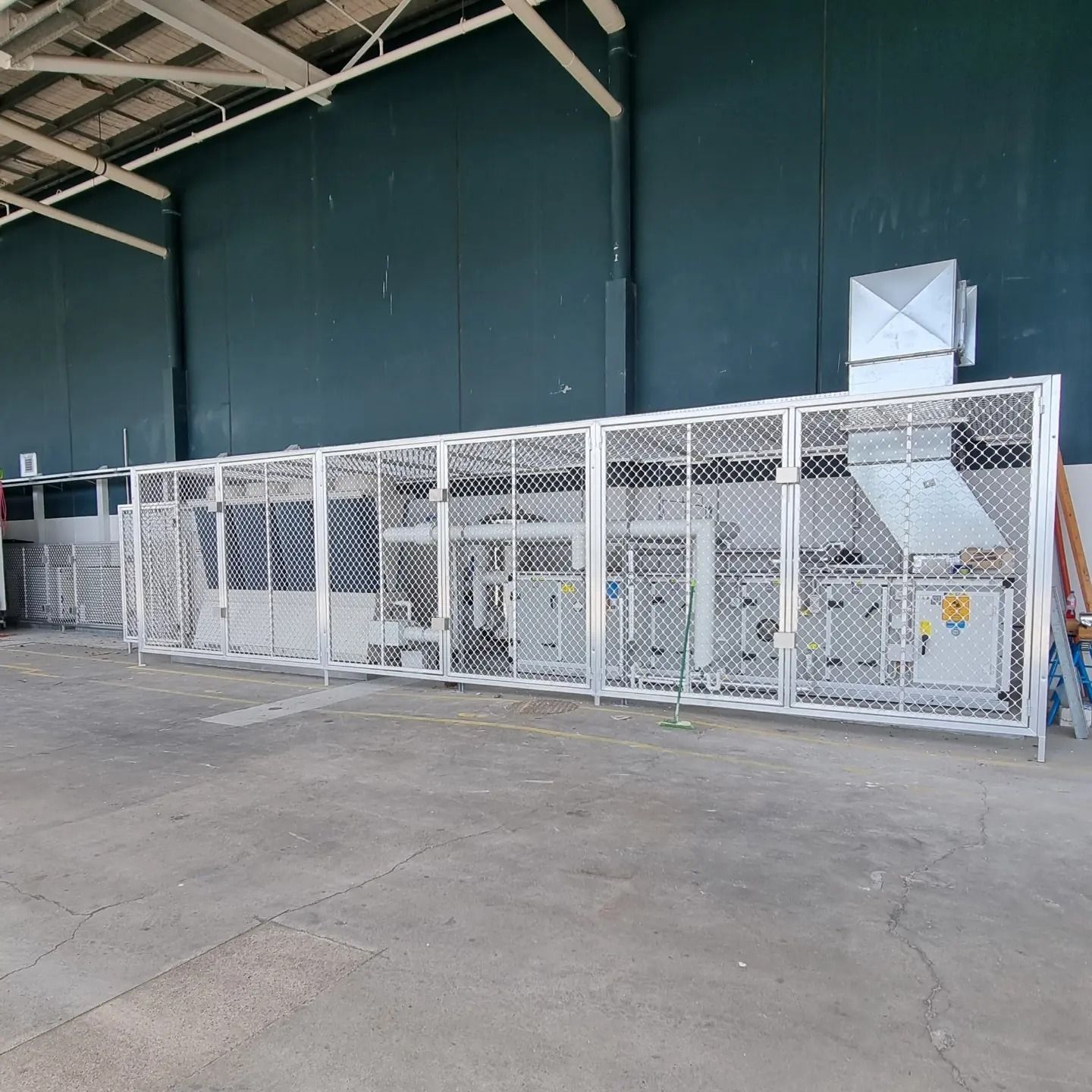 Metal Cage Enclosing Industrial Machinery in A Warehouse — Mingweld Fabrication in Bungalow, QLD