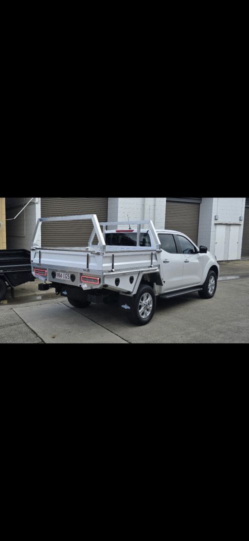 A white pickup truck with an aluminum flatbed tray and ladder rack parked in an outdoor lot.