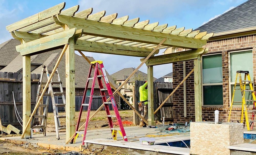 Pergola being built on a patio. Yellow and red tools surround the wood frame.