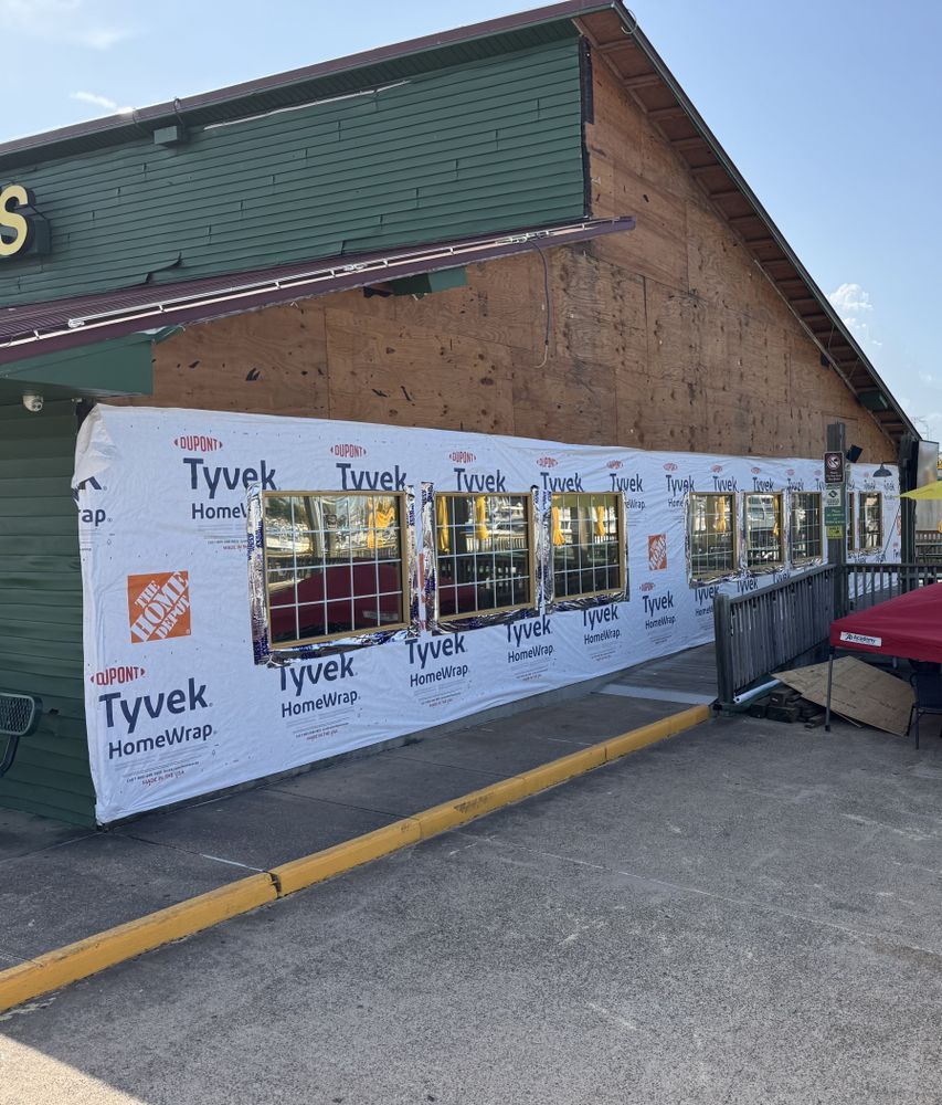 Exterior of a building under construction, Tyvek wrap over window frames, wooden siding.