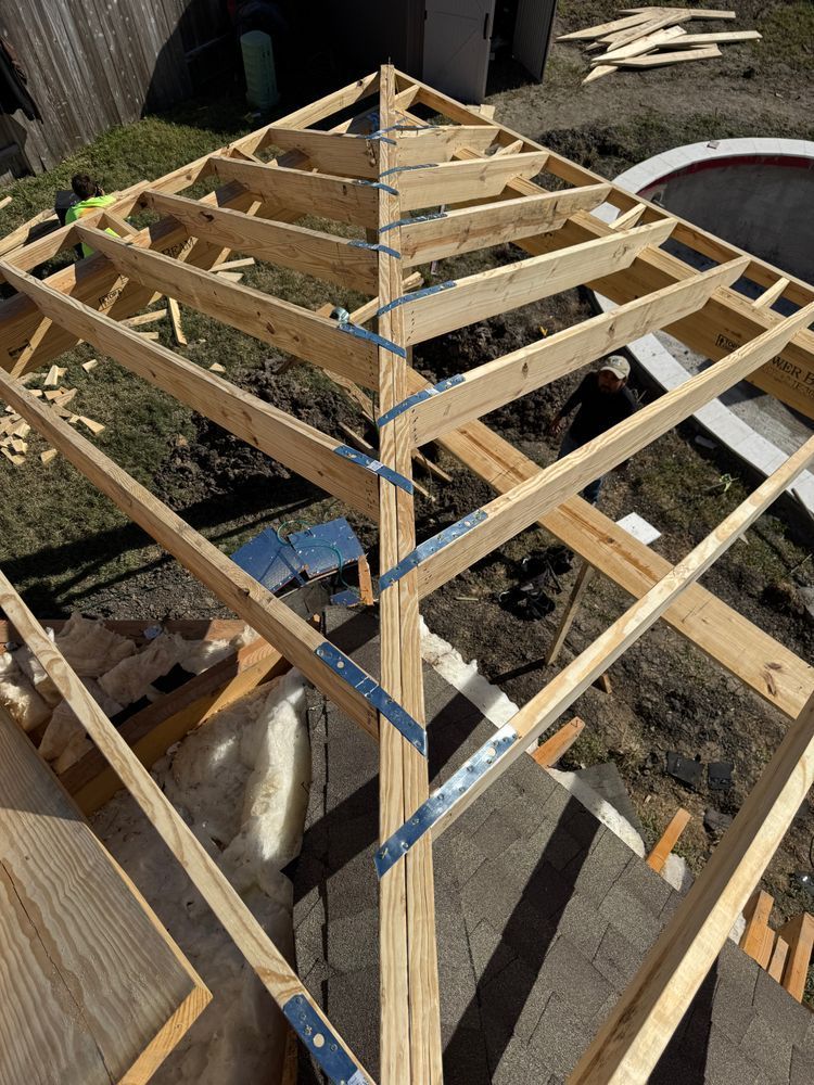 Wooden gazebo roof frame under construction; metal brackets connect beams.