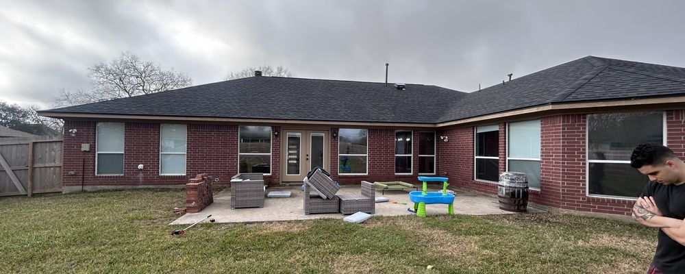Backyard with brick house, patio furniture, and a person. Overcast sky.