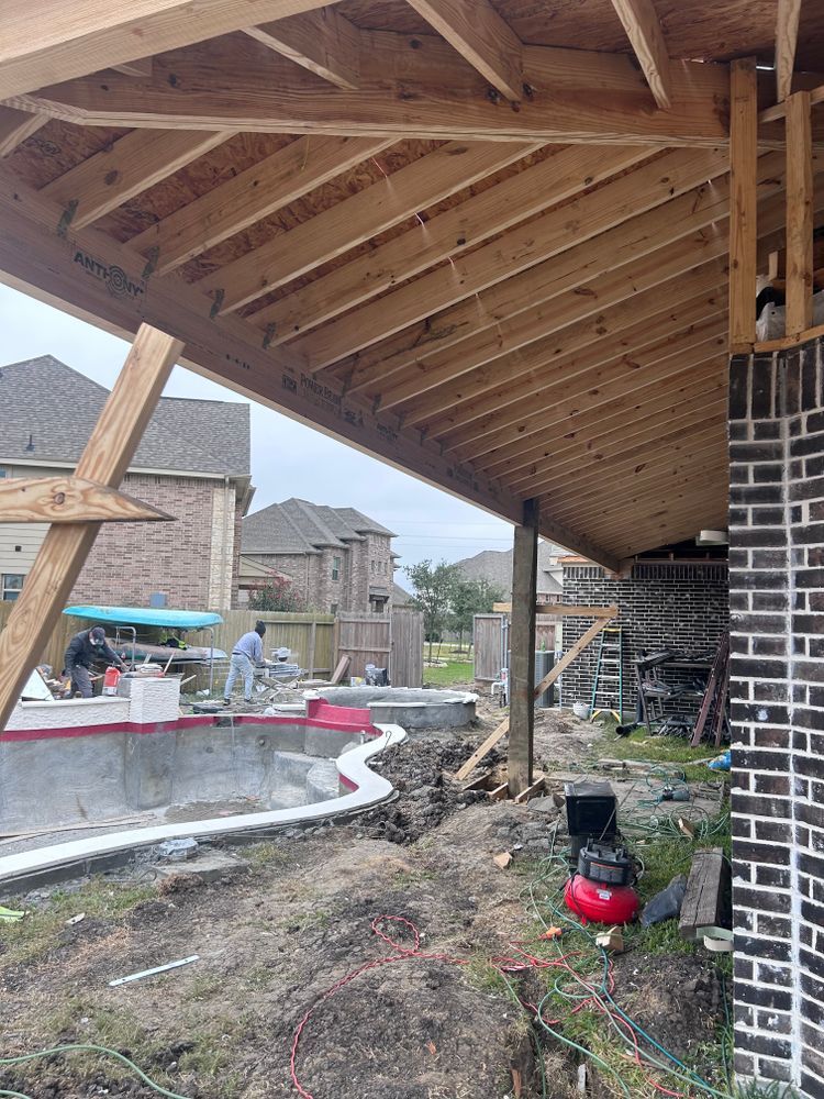 Construction of a patio cover with a pool being built in the background.