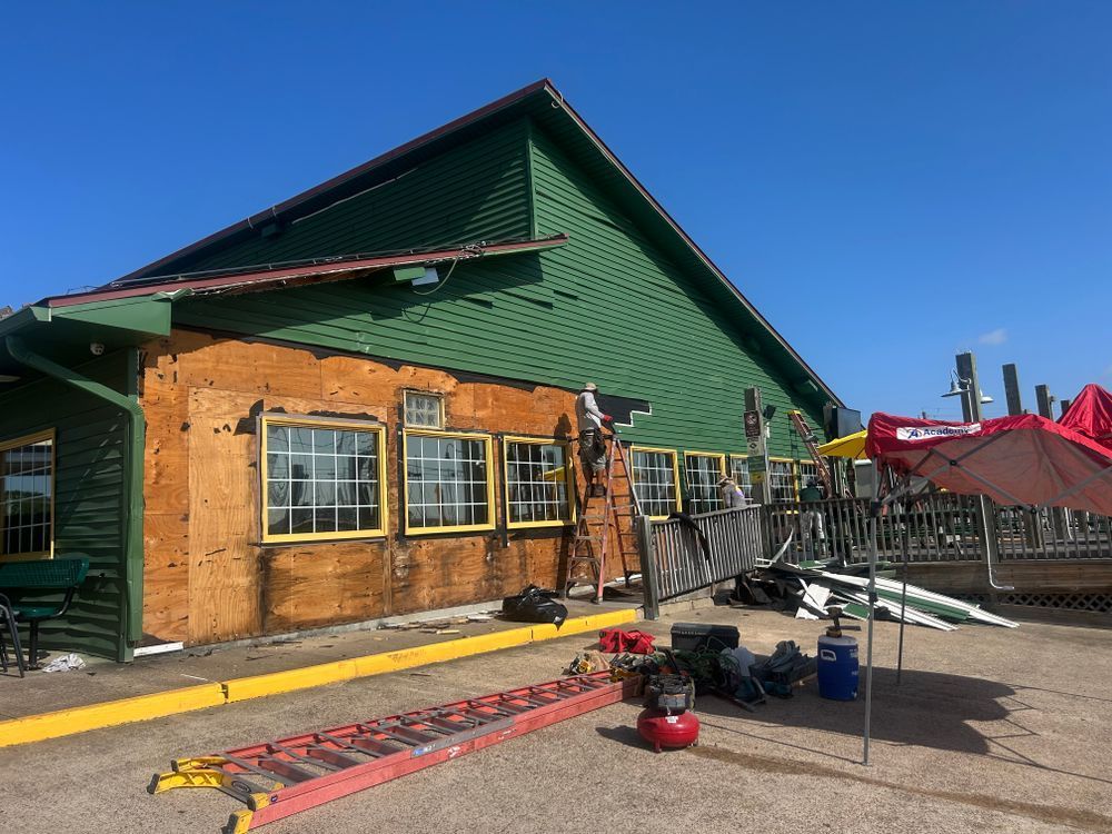 Building under renovation, yellow and green exterior, ladder, equipment, workers, clear sky.