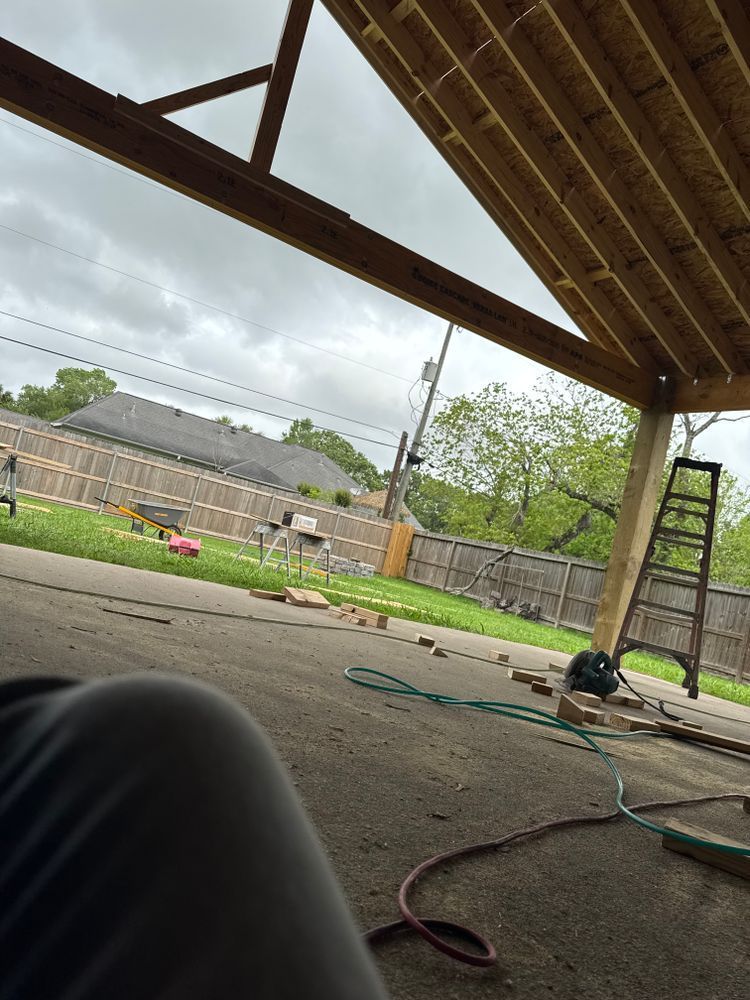 Construction site; unfinished patio cover with wooden beams and a ladder, overcast sky.
