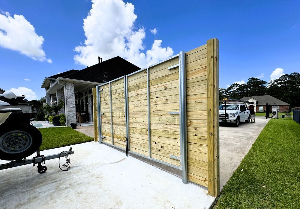 Wooden fence with metal posts and a white truck parked on a driveway, sunny day.