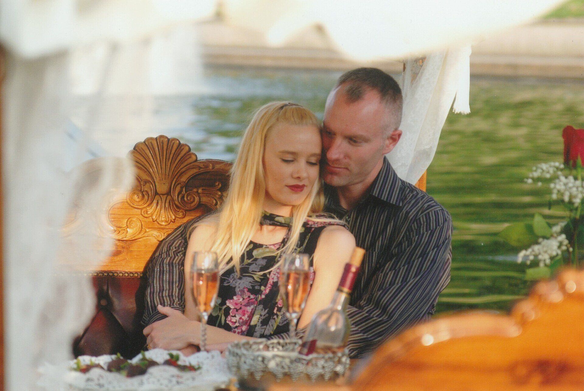 Couple sitting together outdoors at a decorated table, with a blurred garden background.