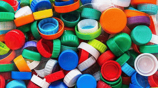 Animated recycled plastic bottle caps falling into a collection pile, illustrating Brava Roofing’s sustainable materials process.