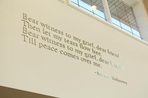 Wall quote in gold lettering on a white wall, ending with a small signature.