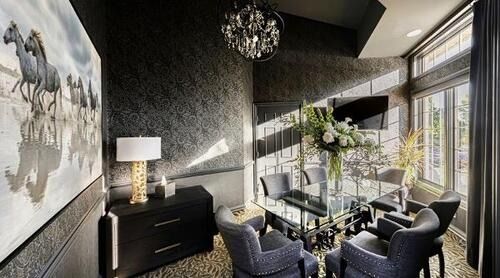 Modern living room with black walls, glass dining table, gray chairs, and large windows with city views