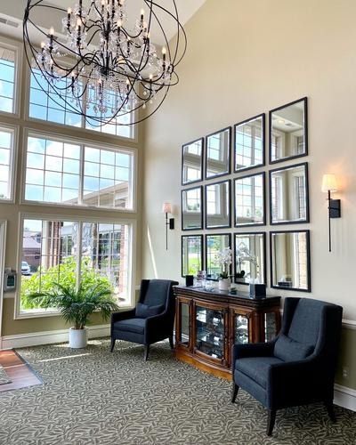 Elegant lobby seating area with black chairs, mirrored wall decor, chandelier, and large windows.