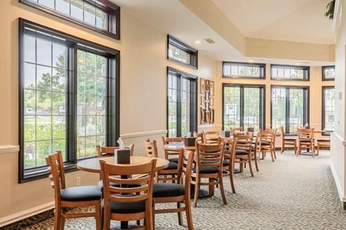 Bright dining room with wooden tables and chairs by large windows