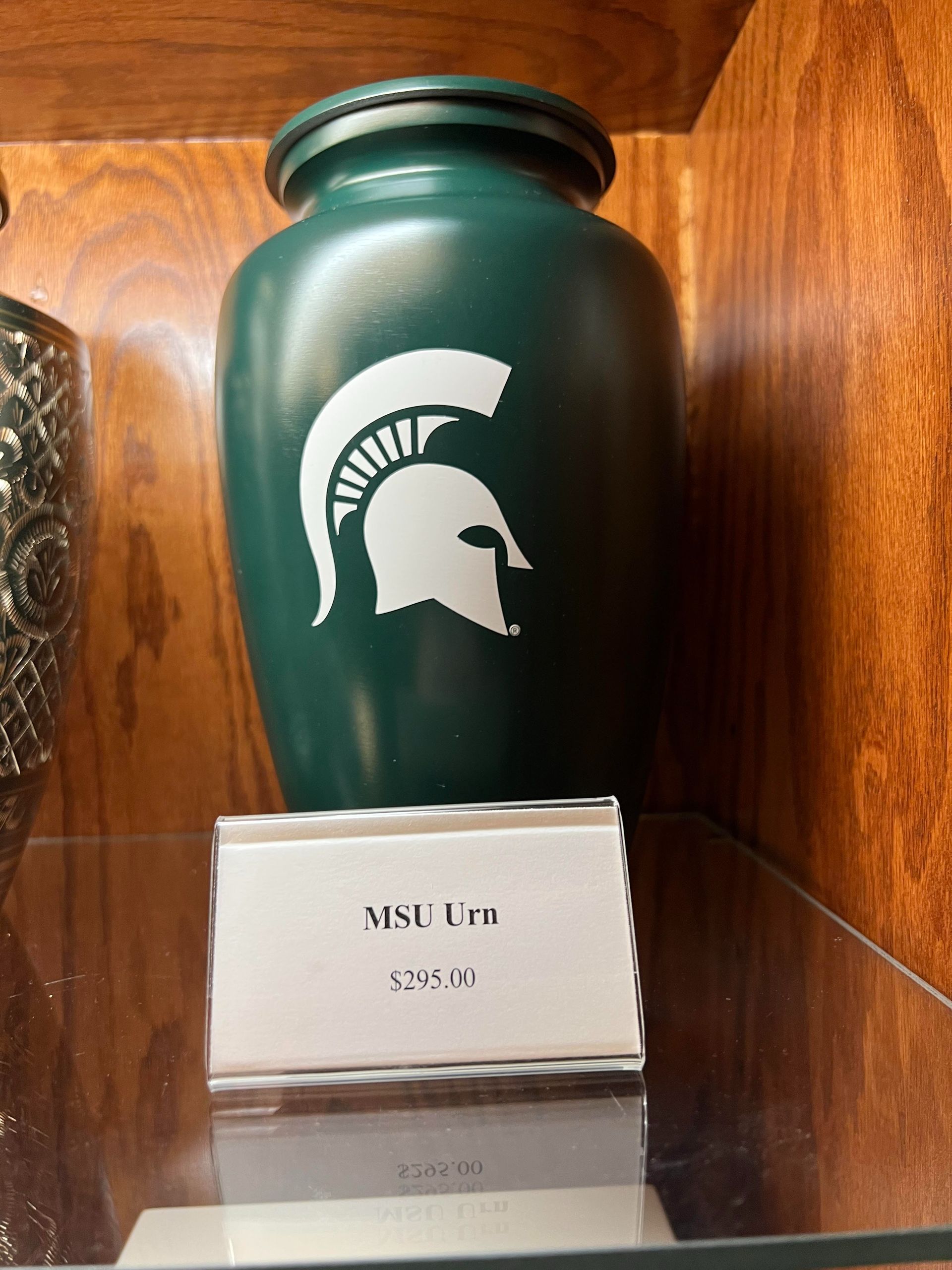 Green water bottle with white Michigan State Spartans logo on a shelf, with a small label below.
