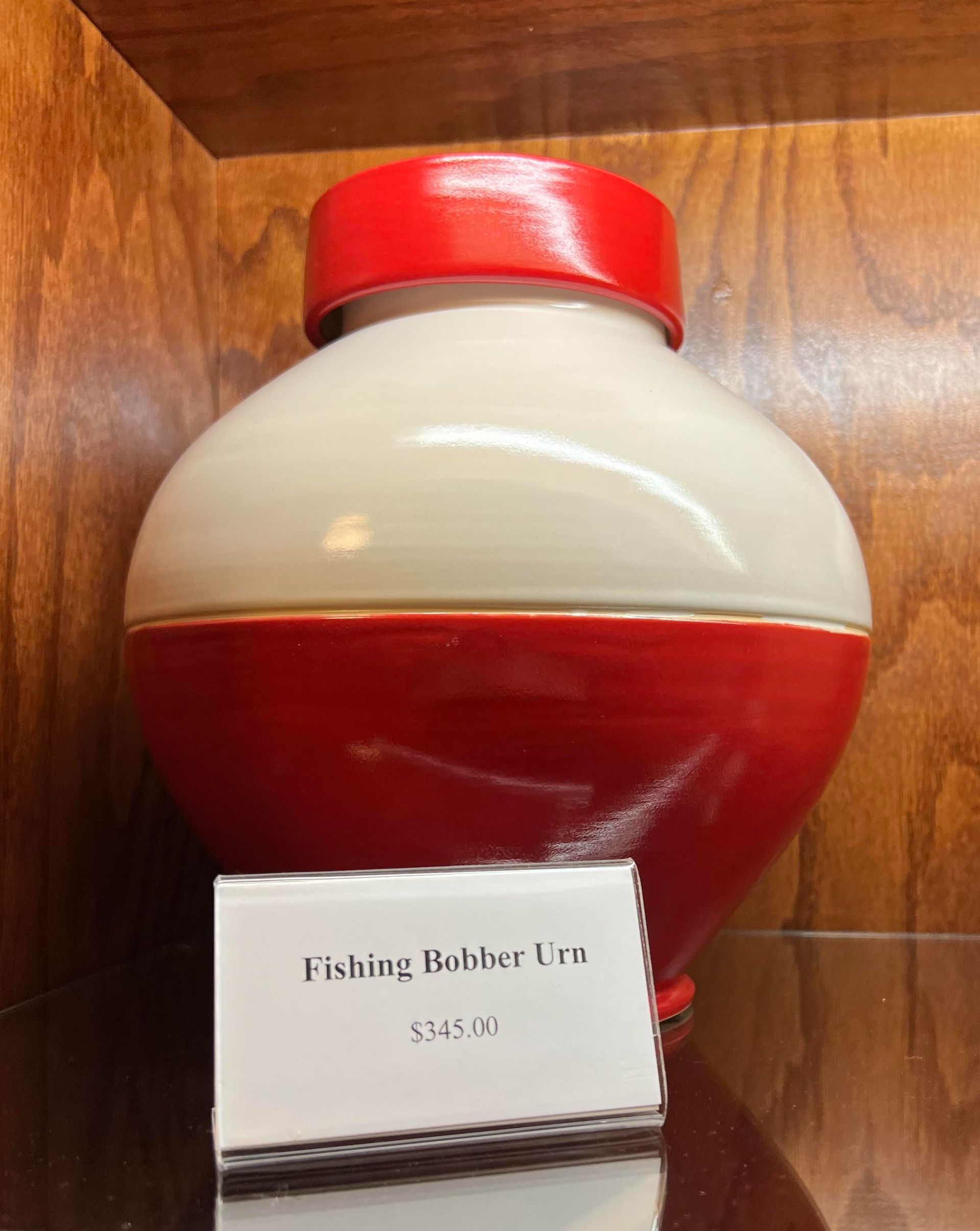 Red-and-white fishing bobber vase displayed on a shelf with a small price tag.
