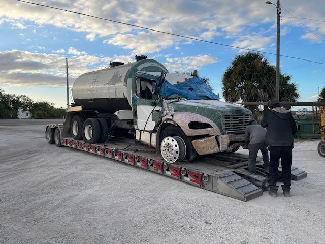 A tanker truck is sitting on top of a trailer in a parking lot.