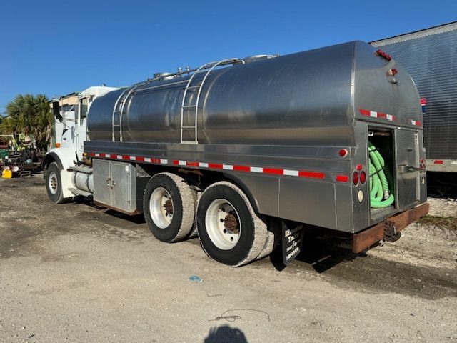 A stainless steel tanker truck is parked in a parking lot