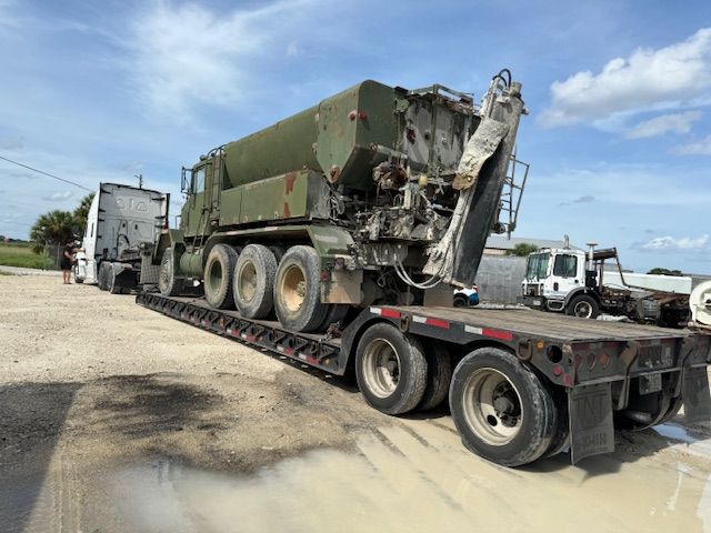 A large military vehicle is being transported on a trailer.