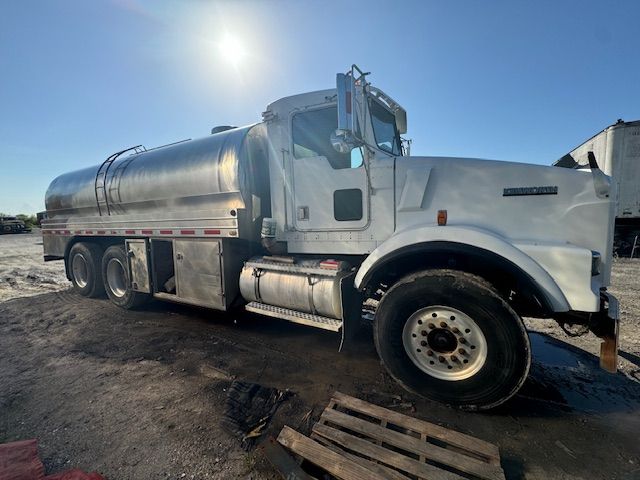 A white tanker truck is parked in a parking lot.