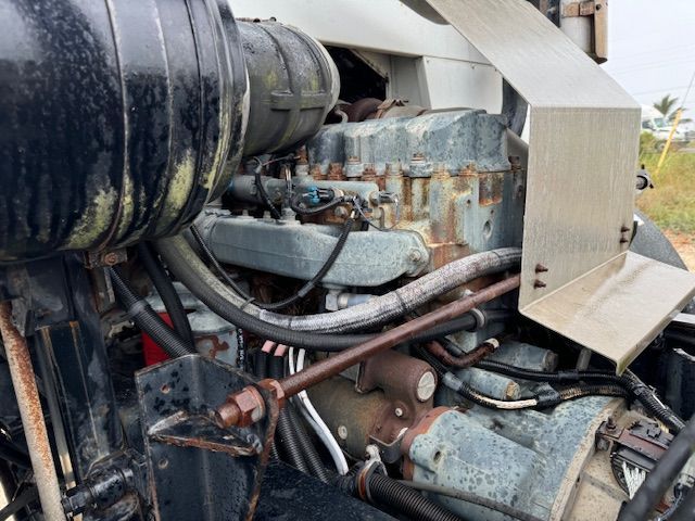 A close up of a tractor engine with a hose coming out of it.