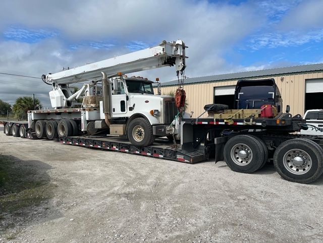 A semi truck is carrying a crane on a trailer.