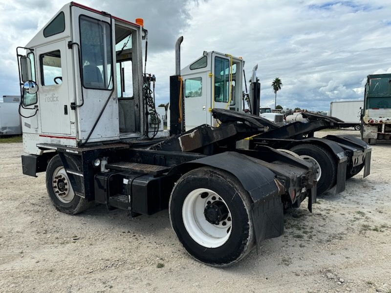 A white and black truck is parked in a dirt lot.