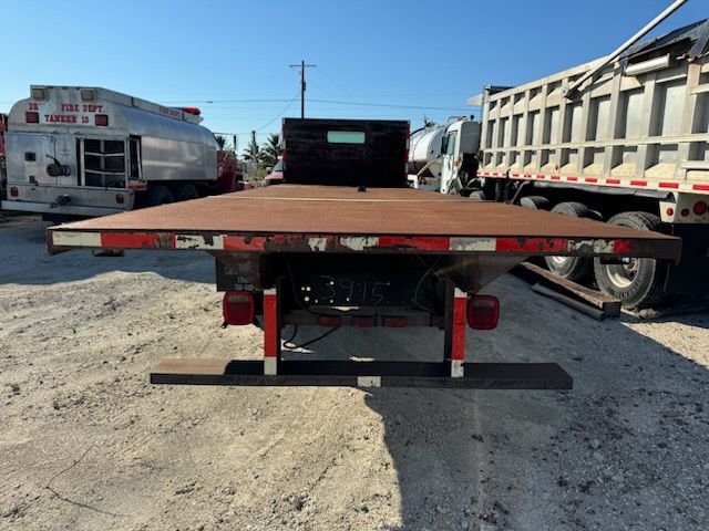 A flatbed truck is parked next to a dump truck