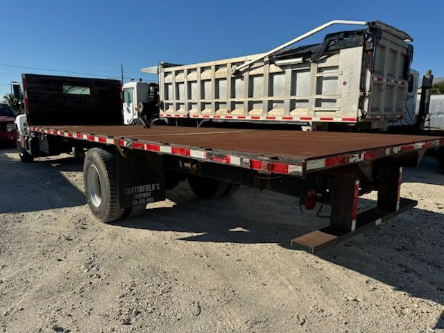 A flatbed truck is parked next to a dump truck