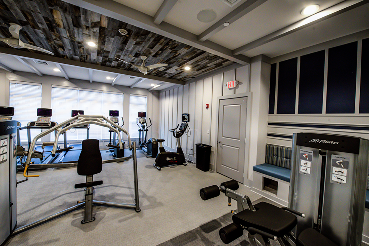 A gym with a lot of equipment and a wooden ceiling.