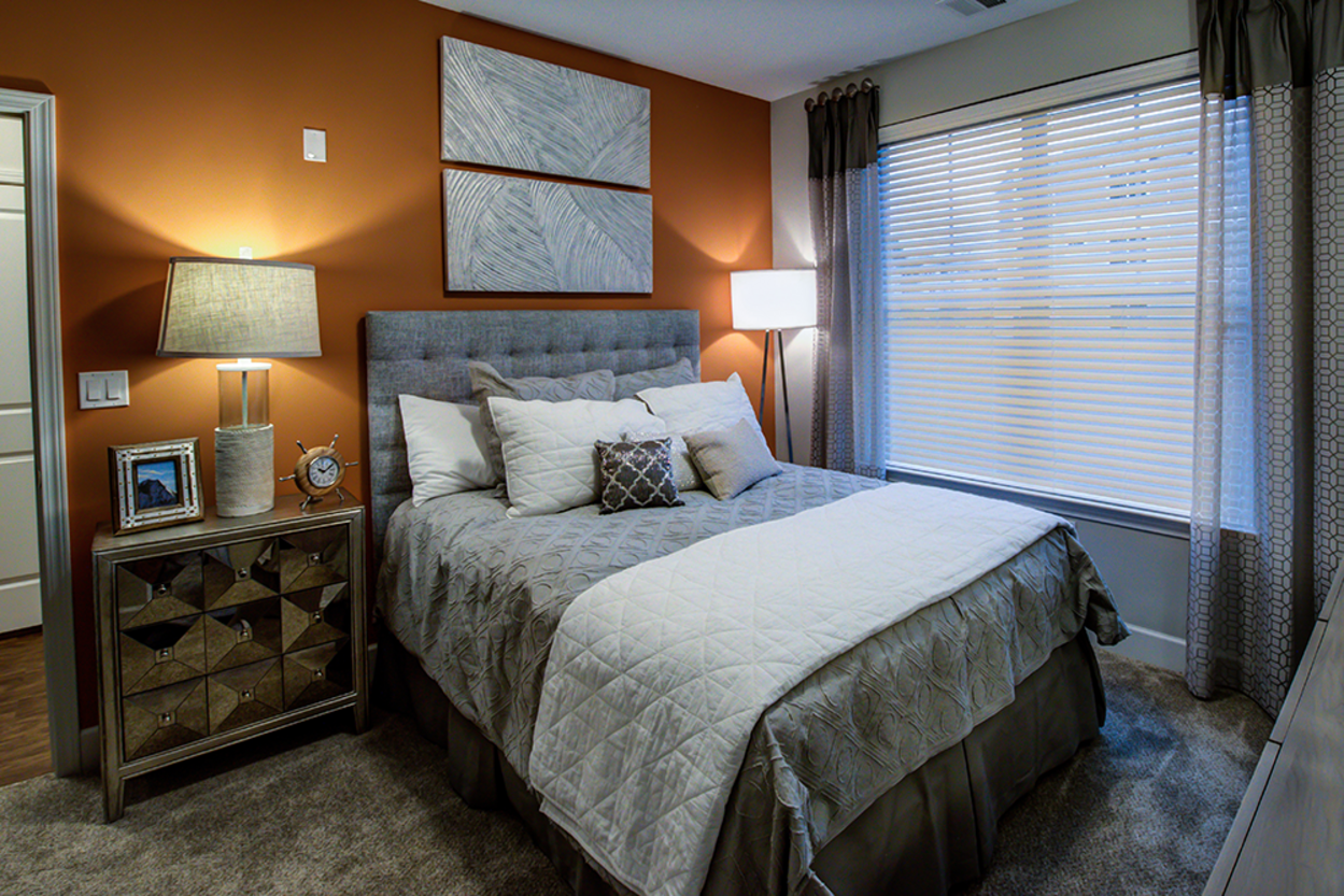 A bedroom with a bed , nightstand , lamps and a window.