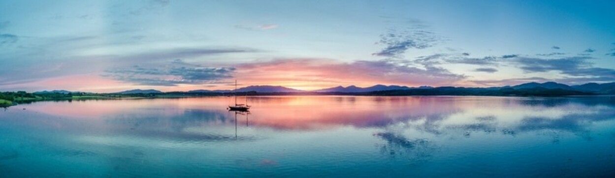 A sunset over a lake with a boat in the water.
