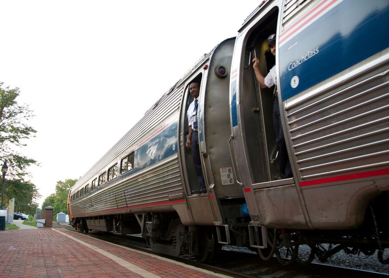 A silver and blue train with the word amtrak on the side