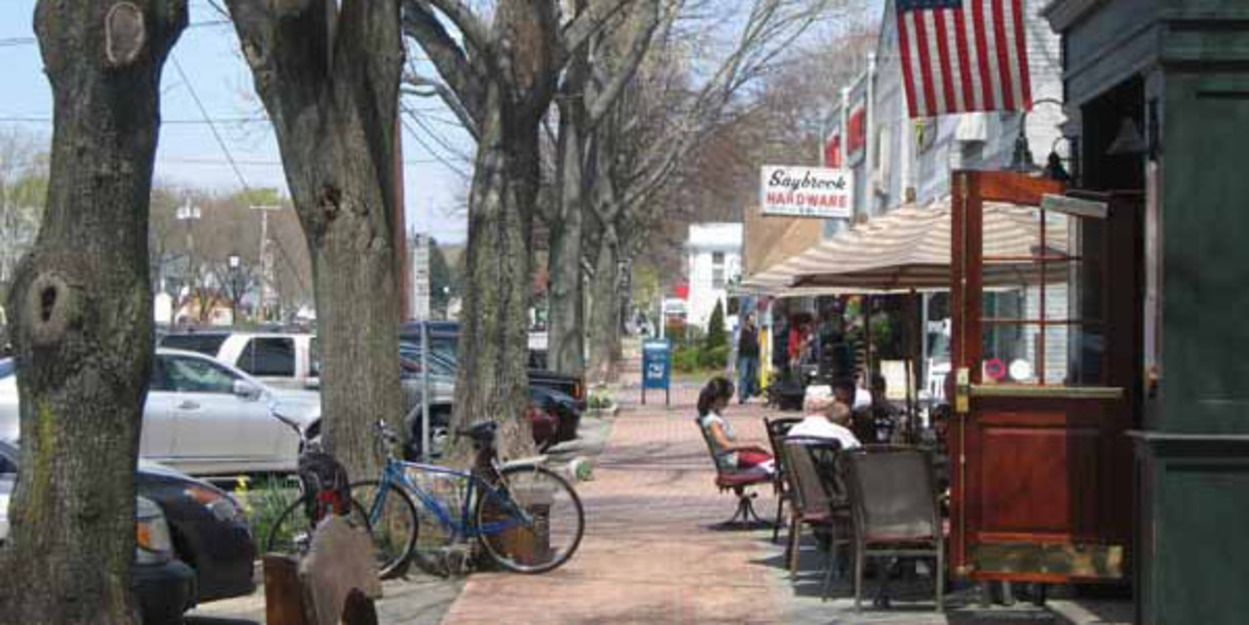 A row of trees along a sidewalk in a small town