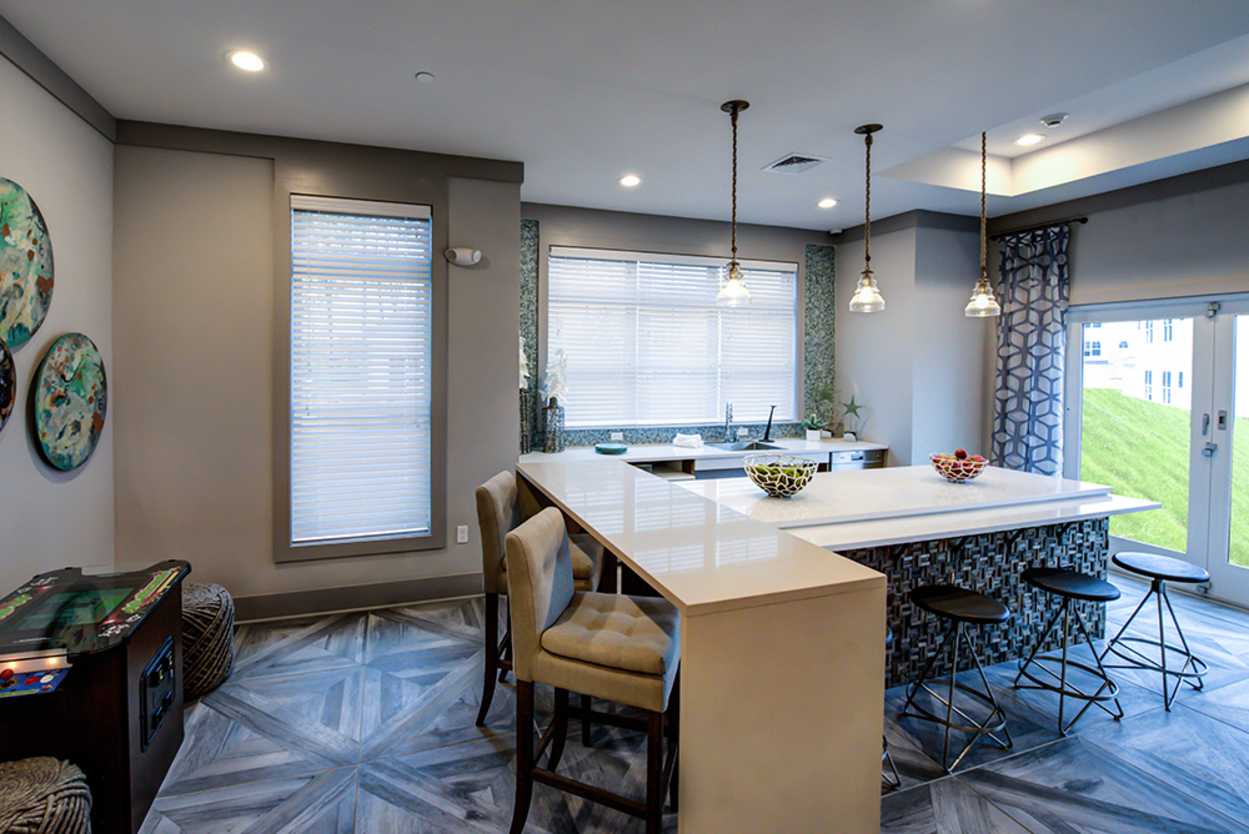 A kitchen with a long counter and chairs in a house.