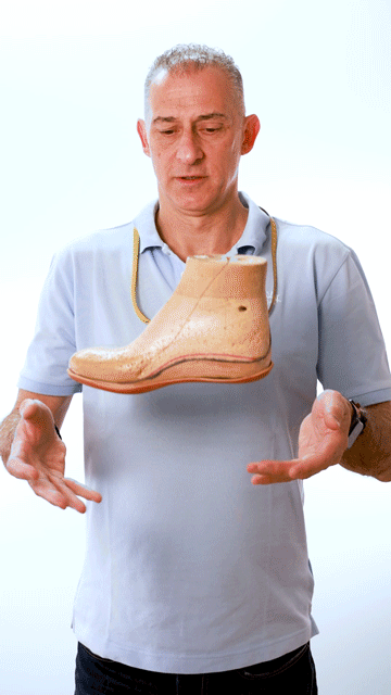 Un homme en chemise bleue tient une chaussure dans ses mains