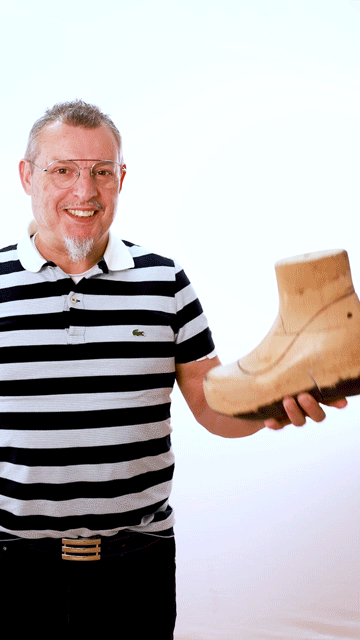 Un homme en chemise rayée tient un sabot dans ses mains.