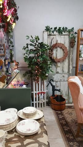 A room with plates , bowls , a chair and a wreath on the wall.