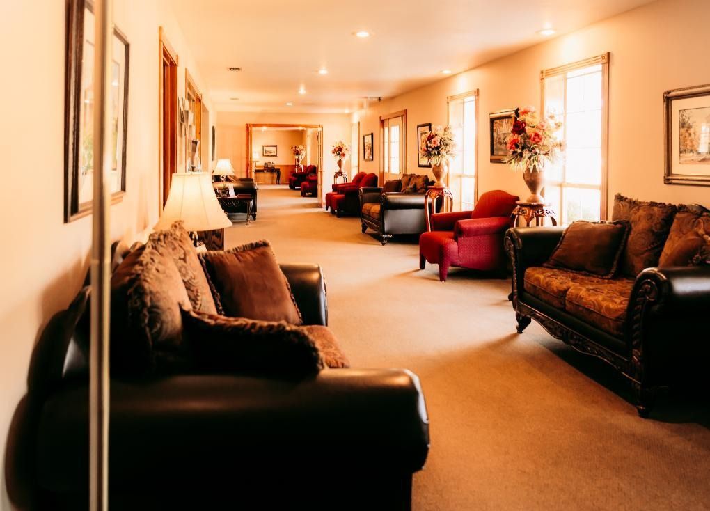 Warm-lit hotel lounge with sofas, lamps, and framed artwork along a carpeted hallway