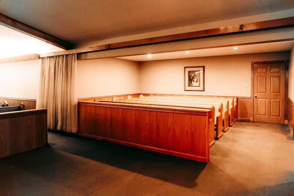 Cozy basement room with wooden benches, carpeted floor, curtains, and a closed door