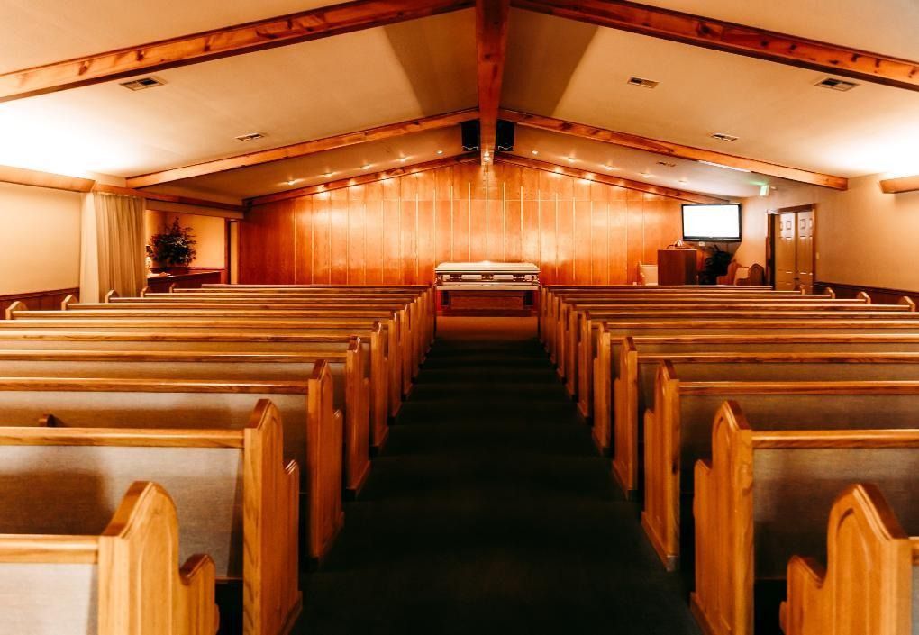 Wood-paneled church interior with rows of wooden pews facing the altar