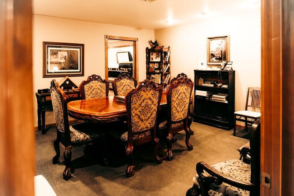 Elegant dining room with ornate chairs, oval table, framed art, and a sideboard under warm lighting