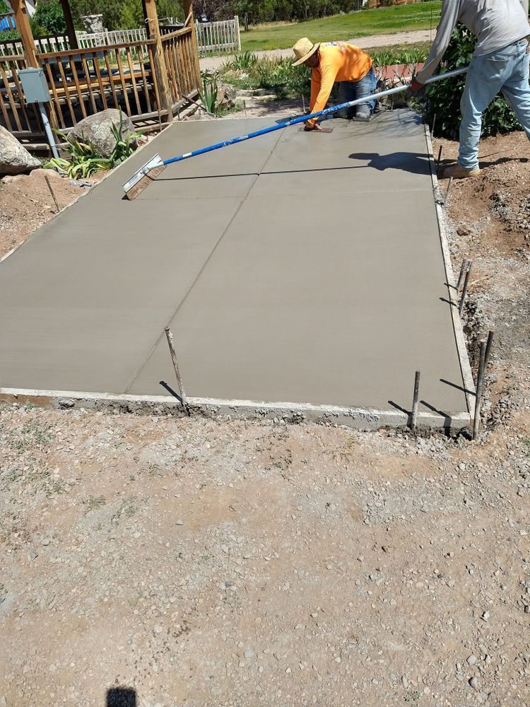 Two workers smoothing wet concrete sidewalk outdoors.