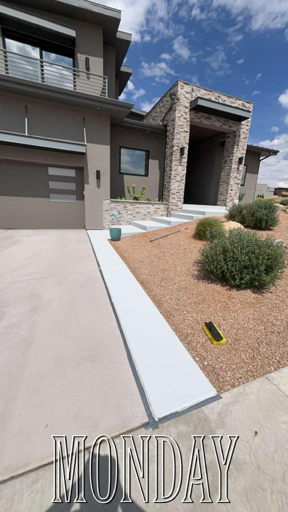 Modern house with gray exterior, stone facade, and walkway, in front yard with bushes.