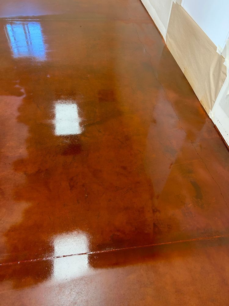 Glossy, brown metallic epoxy floor reflecting light from a window and ceiling.